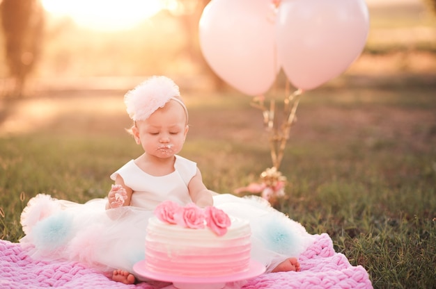 Petite fille mangeant un gâteau d'anniversaire crémeux avec des ballons roses