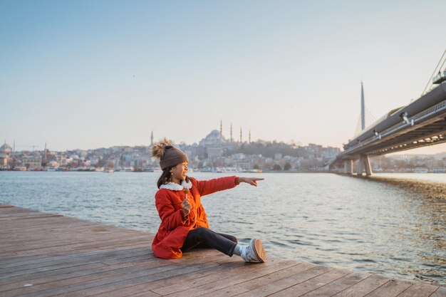 Photo une petite fille avec un manteau rouge assise tout en regardant le beau bosphore istanbul turquie