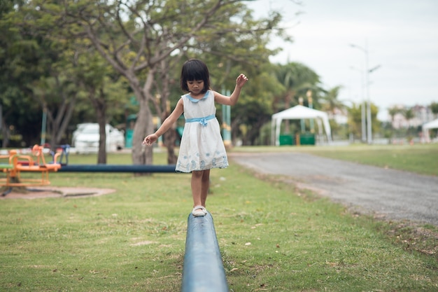 Petite fille marchant sur une bûche dans le parc.