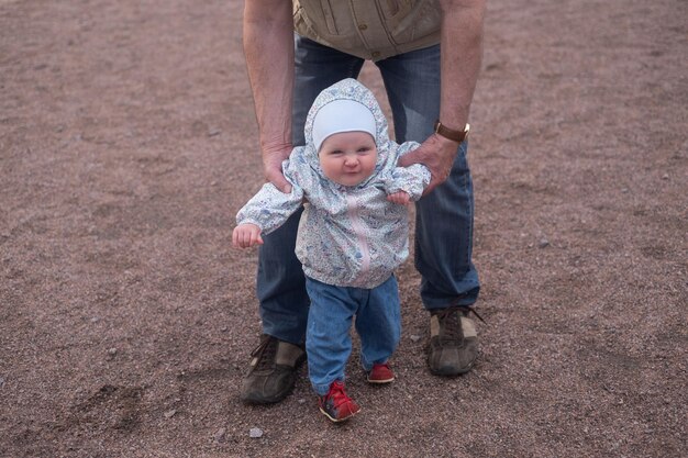 Petite fille marchant à l'extérieur avec un homme Grand-père aidant sa petite-fille à marcher