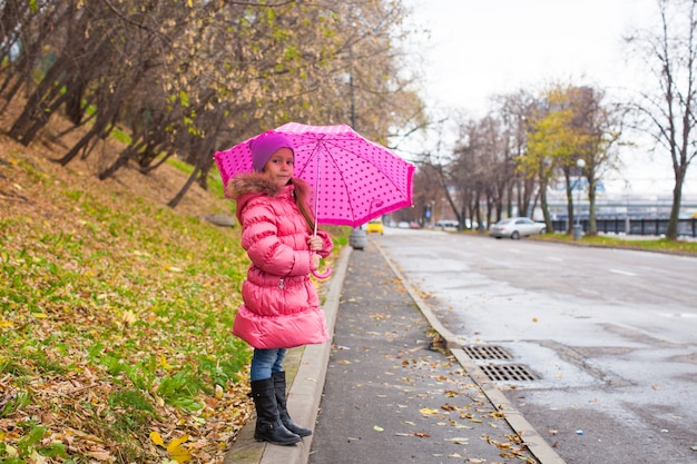 Petite fille marchant sous un parapluie au jour de pluie d'automne