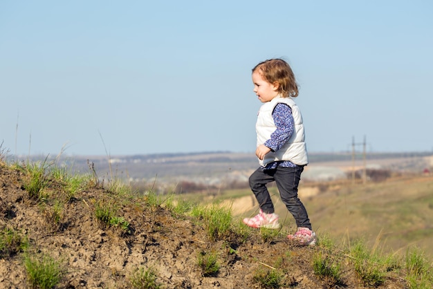 La petite fille marche sur une colline dehors