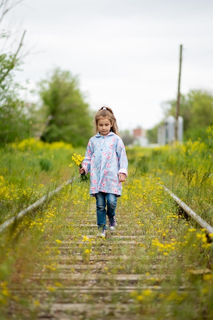 Une petite fille marche le long des voies ferrées herbeuses Écologie