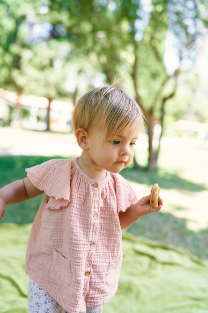 La petite fille marche sur une pelouse verte avec une crêpe