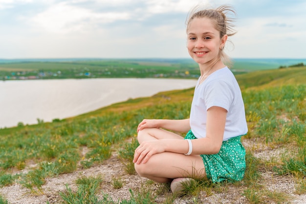 Petite fille marche sur un pré vert avec vue sur le paysage vallonné