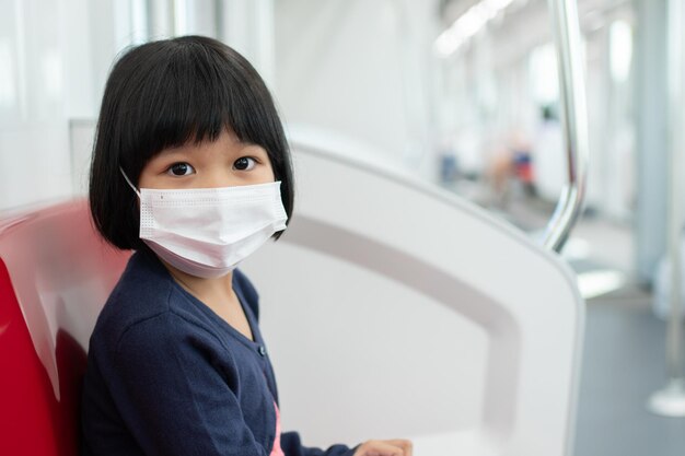 Petite fille avec masque chirurgical protection du visage grippe et épidémie de virus dans les transports publics