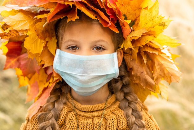 Une petite fille avec un masque médical sur son visage.