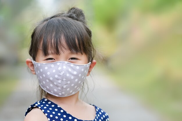 Petite fille a un masque en tissu sur le nez pour une activité de sécurité en plein air, une maladie à coronavirus ou la pollution de l'air