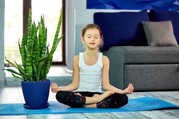 Petite fille méditant en posture de lotus avec les yeux fermés