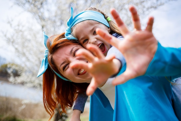 Une petite fille et une mère femme se promènent dans la forêt printanière avec des arbres en fleurs, riant et jouant, le début du printemps, les vacances en famille, l'amour des parents