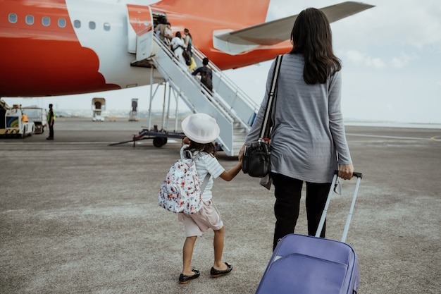 Petite fille et mère tenant par la main marchent vers l'avion