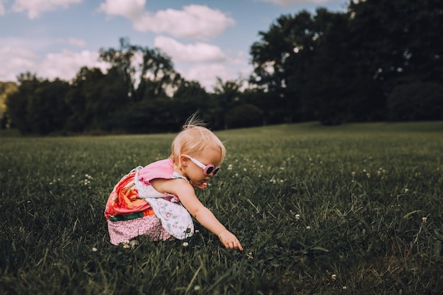 Une petite fille mignonne accroupi sur un champ d'herbe