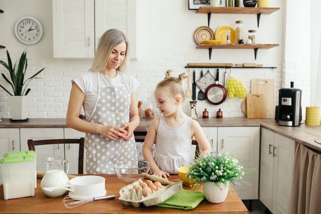 Une petite fille mignonne aide maman à faire des biscuits dans la cuisine. Famille heureuse. Tonifiant.