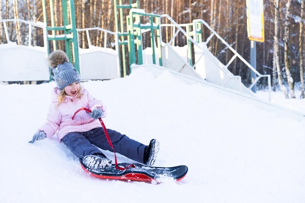 Petite fille mignonne apprenant à monter des sports d'hiver de snowboard pour enfants pour la sécurité des enfants actifs