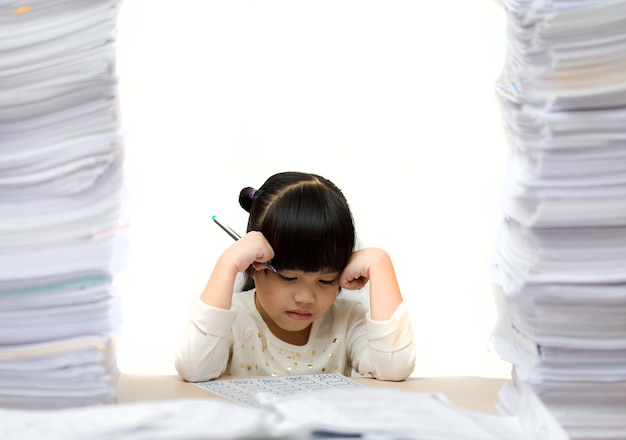 Petite fille mignonne asiatique, faire ses devoirs. gros fardeau pour les étudiants. enfant surchargé