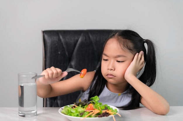 Petite fille mignonne asiatique refuse de manger des légumes sainsNutrition de saines habitudes alimentaires pour les enfants conceptLes enfants n'aiment pas manger de légumes