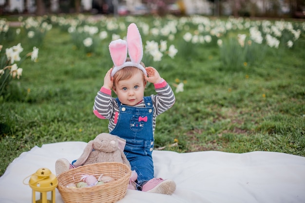 Petite fille mignonne assise sur l'herbe près des jonquilles