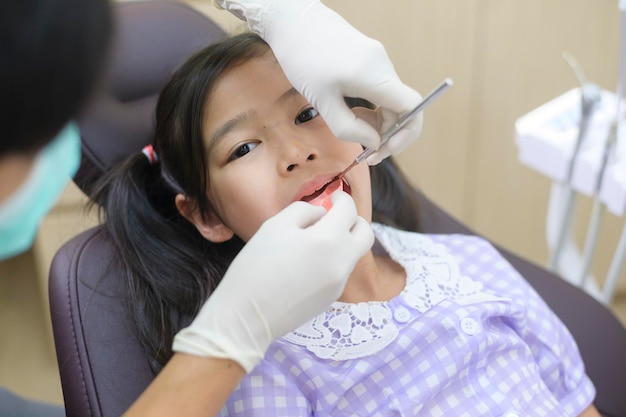 Une petite fille mignonne ayant des dents examinées par un dentiste lors d'un examen des dents d'une clinique dentaire et d'un concept de dents saines