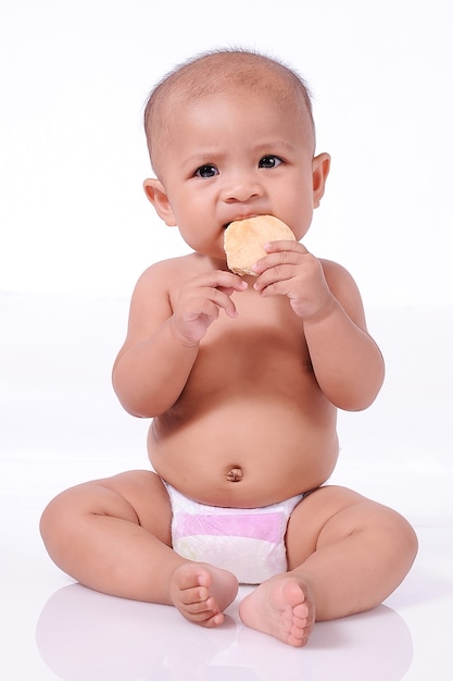 Une petite fille mignonne de bébé asiatique mangeant des biscuits portant des couches