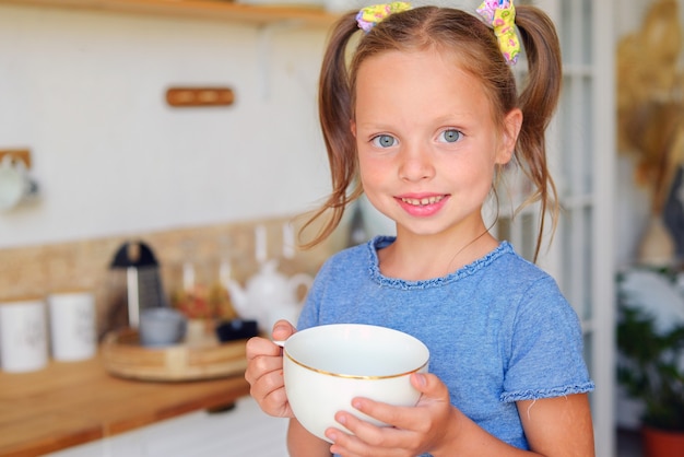 petite fille mignonne buvant du thé au citron dans la cuisine enfance heureuse