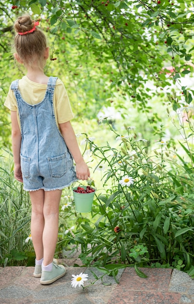 La petite fille mignonne choisit une cerise d'un arbre dans le jardin de cerise