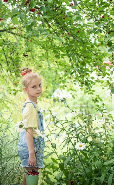 La petite fille mignonne choisit une cerise d'un arbre dans le jardin de cerise