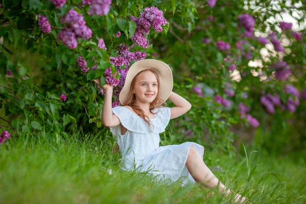 Petite fille mignonne dans un chapeau de paille au printemps dans le jardin lilas