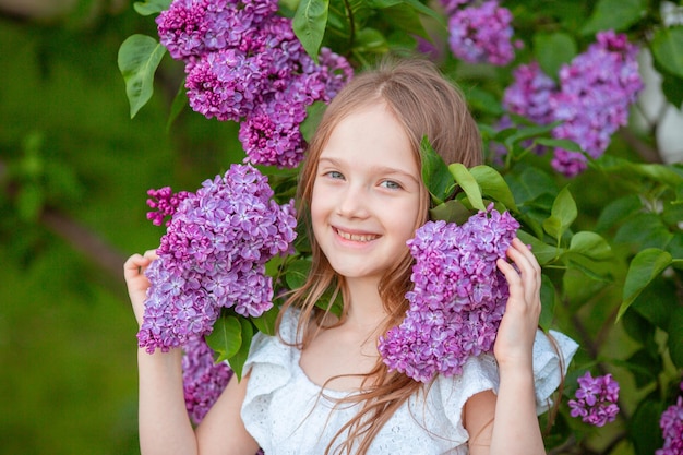 Petite fille mignonne dans un lilas en fleurs au printemps