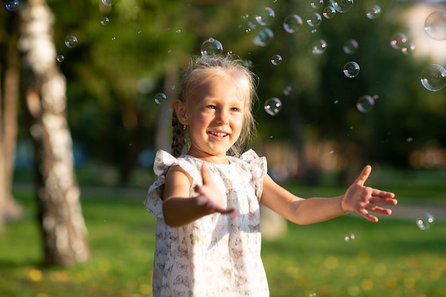 Petite fille mignonne dans le parc d'été soufflant des bulles et s'amusant.