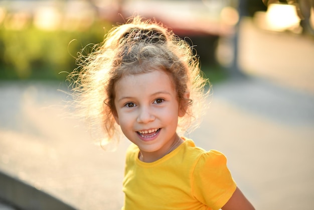 Une petite fille mignonne dans un T-shirt jaune sur fond d'arbres verts