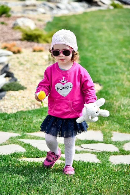 Une petite fille mignonne dans une veste rose et un chapeau rose se promène dans la ville Enfance heureuse