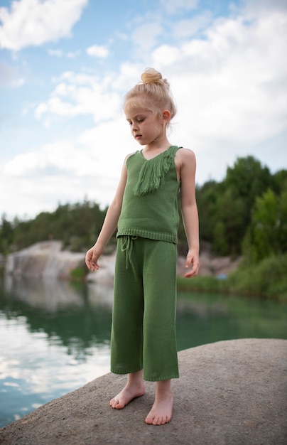 Petite fille mignonne dans des vêtements élégants dans un paysage de nature