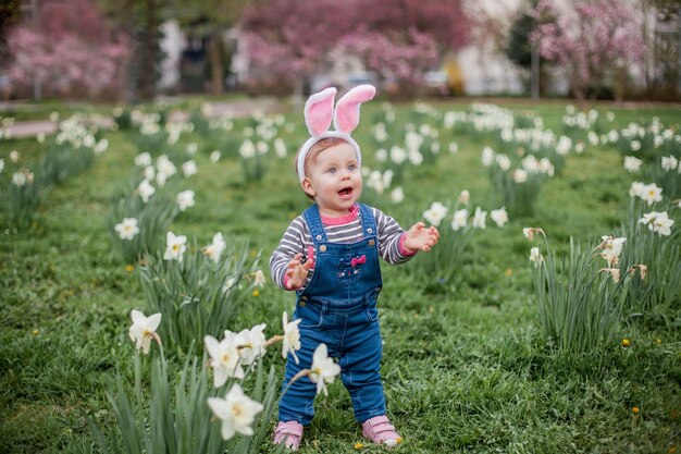 Petite fille mignonne debout sur l'herbe près des jonquilles