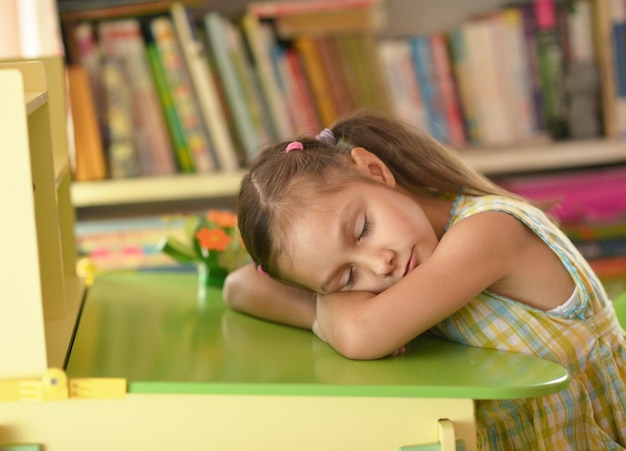 Petite fille mignonne dormant sur le livre à la maison