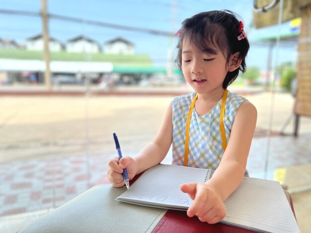 La petite fille mignonne écrit sur son cahier