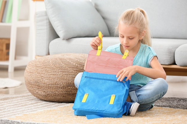 Petite fille mignonne emballant le cartable à la maison