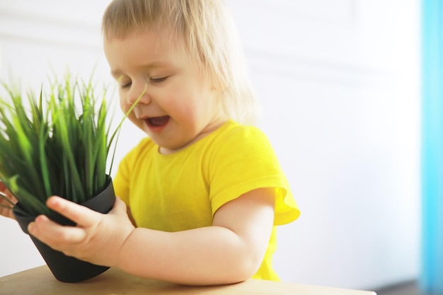 Petite fille mignonne d'enfant en bas âge ayant l'amusement tenant le pot avec la fleur plantée à la maison. Concept de soins aux fleurs et à la nature. Enfants et famille enfance heureuse.