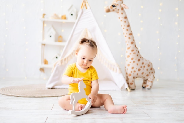 Une petite fille mignonne est assise dans une salle de jeux lumineuse et confortable pour enfants Textiles pour enfants