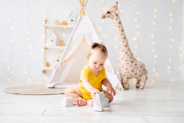 Une petite fille mignonne est assise dans une salle de jeux lumineuse et confortable pour enfants Textiles pour enfants