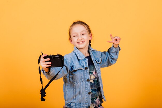 Une petite fille mignonne faisant la photo sur un mur jaune.