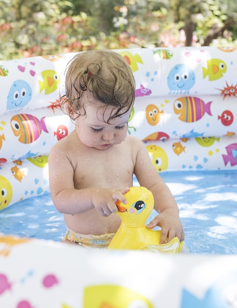 Petite fille mignonne jouant dans une piscine gonflable colorée