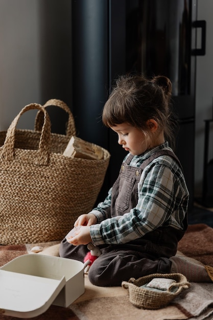 petite fille mignonne jouant avec des jouets miniatures à la maison sur le sol fille élégamment habillée avec de l'artisanat en bois et des jouets faits maison