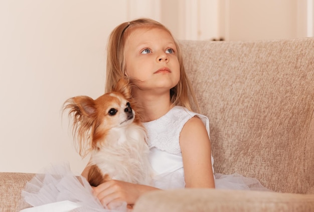 Une petite fille mignonne joue avec un chien chihuahua dans un salon