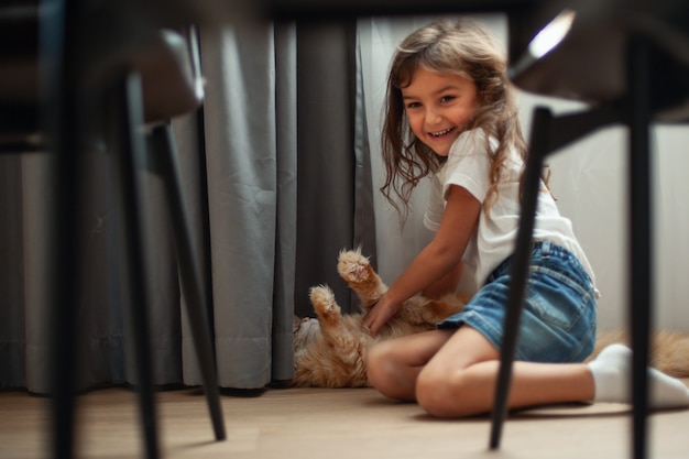 Petite fille mignonne joue sur le sol avec un chat Maine Coon. Concept d'animaux de compagnie.