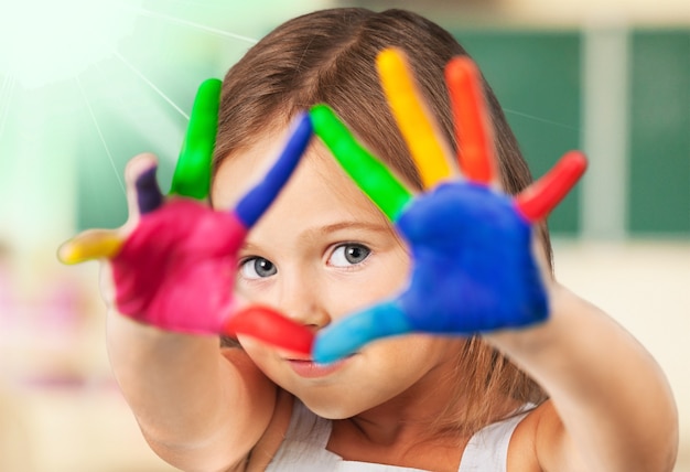 Petite fille mignonne avec les mains peintes colorées sur le fond de classe