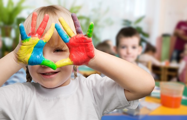 Petite fille mignonne avec les mains peintes colorées sur le fond de classe