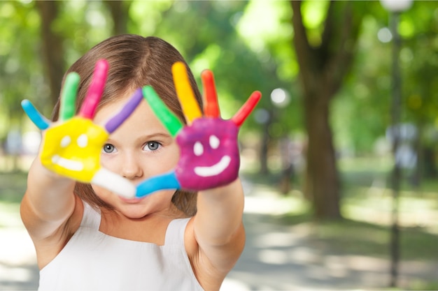 Photo petite fille mignonne avec les mains peintes colorées sur le fond