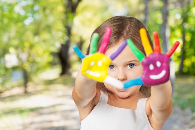 Petite fille mignonne avec les mains peintes colorées sur le fond