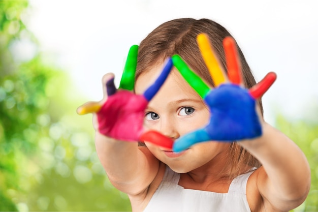 Petite fille mignonne avec les mains peintes colorées sur le fond