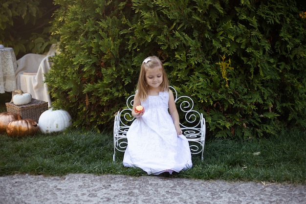 Petite fille mignonne mange une pomme dans le jardin